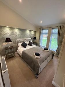 a bedroom with a large bed and two windows at Relaxing Woodland Retreat in Eaton