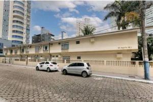 deux voitures garées devant un bâtiment dans une rue dans l'établissement Ap em Balneário Camboriú, à Balneário Camboriú