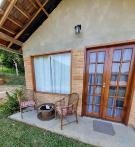 a patio with two chairs and a fire pit at Chalé Quinta Garden in Nova Friburgo