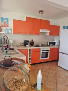 eine Küche mit orangefarbenen Schränken und einem weißen Kühlschrank in der Unterkunft Villa avec vue T2 à T5 Duo de la Baie in Le Robert