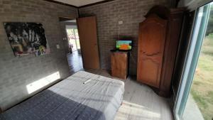 um quarto com uma cama, um armário e uma televisão em Casa en la Bota, Manantiales em Manantiales