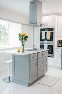 a white kitchen with a vase of flowers on a counter at Seahorse Cottage - Pool Home in Naples