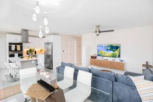 a living room with a blue couch and a kitchen at Seahorse Cottage - Pool Home in Naples