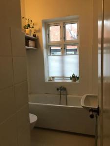 a bathroom with a tub and a window and a toilet at Vidunderligt byhus, 180m2 i hjertet af Esbjerg. in Esbjerg