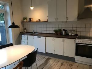 a kitchen with white cabinets and a table with chairs at Vidunderligt byhus, 180m2 i hjertet af Esbjerg. in Esbjerg