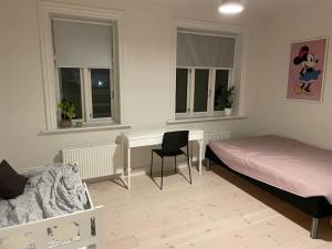 a bedroom with a bed and a desk and two windows at Vidunderligt byhus, 180m2 i hjertet af Esbjerg. in Esbjerg