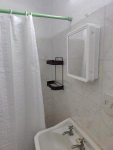 Baño blanco con lavabo y espejo en Acogedora Casa con Jardín, en Maldonado