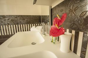 un bagno con lavandino e un fiore rosso in un vaso di Hotel Villa Maranello a Maranello