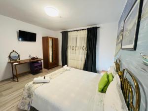 a bedroom with a large white bed and a desk at CASA MATILI-1st floor of the house in Piatra Neamţ