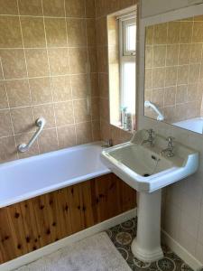 a bathroom with a tub and a sink and a mirror at Millbrook House in Oldcastle