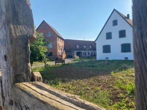a view through a wooden fence of a yard with buildings at Au clos du seltzbach in Hoffen