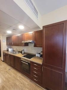 a kitchen with wooden cabinets and a counter top at Lotus Apartments in King Abdullah Economic City