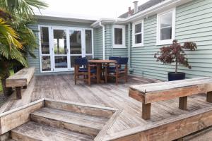 a deck with benches and a table on a house at Kiwi bnb in Matamata