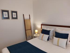 1 dormitorio con 1 cama con almohadas azules y blancas en Mostarda Boutique Apartment en Vila do Conde