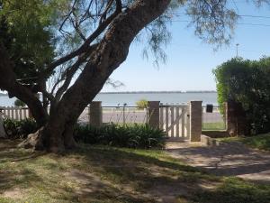 a tree next to a fence and a beach at San Miguel del monte 6 personas con pileta in San Miguel del Monte