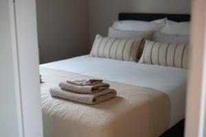 twee witte handdoeken zittend op de rand van een bed bij Huisje Novea in Harderwijk