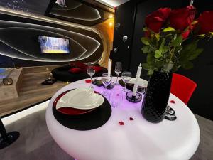 uma mesa branca com copos de vinho e um vaso com flores em Les Secrets Rooms/Love Room em Rivesaltes