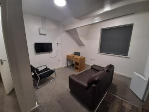 ein Wohnzimmer mit einem Ledersofa und einem Stuhl in der Unterkunft Exclusive Self-contained flat in Middlesbrough in Middlesbrough