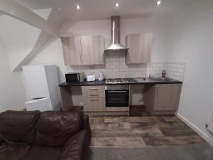 a kitchen with wooden cabinets and a couch in a room at Exclusive Self-contained flat in Middlesbrough in Middlesbrough