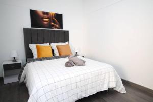 1 dormitorio con 1 cama blanca grande con almohadas de color naranja en Magnifique Appart Cosy Tram 4pers Gare Wifi, en Pierrefitte-sur-Seine