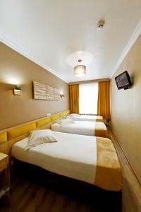 three beds in a room with a window at Hotel de France in Brussels