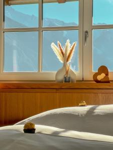 ein Schlafzimmer mit einem Bett und einem Fenster mit einer Blumenvase in der Unterkunft Landhaus Maria in Hippach