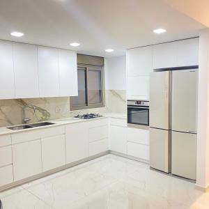 a kitchen with white cabinets and a refrigerator at the pool on the sea in Netanya