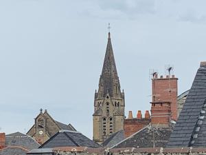 un edificio alto con un campanario en la parte superior de los tejados en appartement de charme centre historique de Brive en Brive-la-Gaillarde