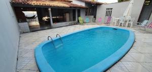 een groot blauw zwembad op een patio bij Casa Temporada Guriri Beach in Guriri