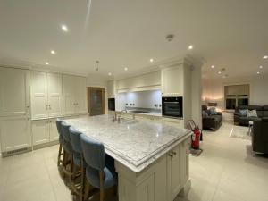 a kitchen with a large island with blue bar chairs at The Last Resort With Hot Tub And Car Service in Warrenpoint