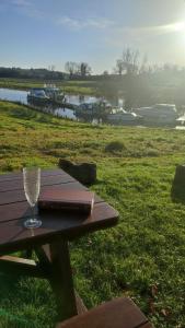 a picnic table with a wine glass and a book at Glamping Pod Thady Killynick County Fermanagh in Killyhevlin