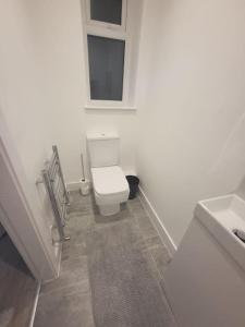 a white bathroom with a toilet and a sink at New 4 bedrm house! Parking. 10min to City / Etihad in Manchester