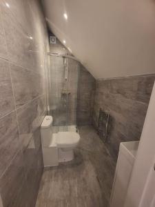 a small bathroom with a toilet and a shower at New 4 bedrm house! Parking. 10min to City / Etihad in Manchester