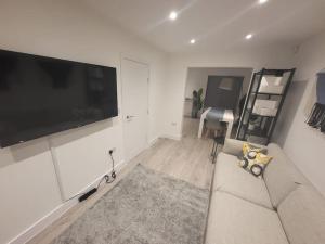 ein Wohnzimmer mit einem Sofa und einem Flachbild-TV in der Unterkunft New 4 bedrm house! Parking. 10min to City / Etihad in Manchester