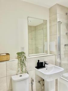 a bathroom with a sink and a toilet and a mirror at High-Spec Skyline Apartment in London - 2 BDR & Balcony in London