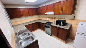 a small kitchen with wooden cabinets and a sink at Master Room with attach Bathroom Near Mall of the Emirates in Dubai
