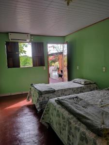 2 camas en una habitación con paredes verdes en Casa Grande Aconchegante en Alter do Chao