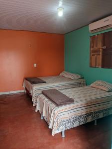 3 camas en una habitación con paredes de color verde y naranja en Casa Grande Aconchegante en Alter do Chao