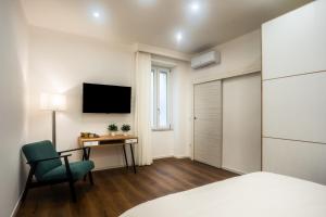 Schlafzimmer mit einem Bett, einem Schreibtisch und einem TV in der Unterkunft La Grande Bellezza in Neapel