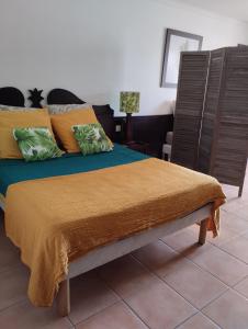 1 dormitorio con 1 cama con manta naranja y silla en Sainte-Anne en Sainte-Anne