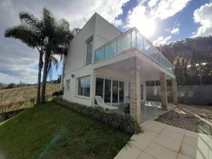 una grande casa bianca con una palma su un prato di Casa de Campo em meio a Vinhedos a Pinto Bandeira