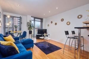 a living room with a blue couch and a table at Spacious 4 Beds Apt - Perfect for Families, Contractors & FREE Parking in Leeds