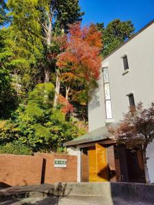 un edificio blanco con puertas y árboles amarillos en 熱海温泉　実の別荘 en Atami