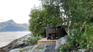 a wooden bench sitting on the side of a body of water at Kråen Gard in Larsnes