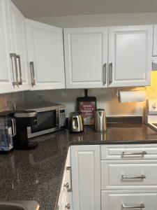 a kitchen with white cabinets and a microwave at Walkout basement apartment in Mississauga