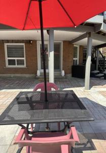 a picnic table with a red umbrella and two chairs at Walkout basement apartment in Mississauga