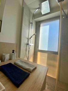 La salle de bains est pourvue d'une douche et d'une serviette bleue sur une table. dans l'établissement Cocon ensoleillé avec parking gratuit, à Nice