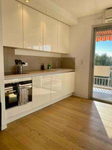 a kitchen with white cabinets and a large window at Cocon ensoleillé avec parking gratuit in Nice
