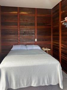 1 dormitorio con 1 cama blanca y paredes de madera en Refúgio Litorâneo em São Chico-Ervino, en São Francisco do Sul