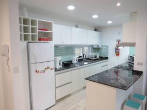 Una cocina con gabinetes blancos y un refrigerador. en Wales Ave. Apartment, en Puerto Madryn